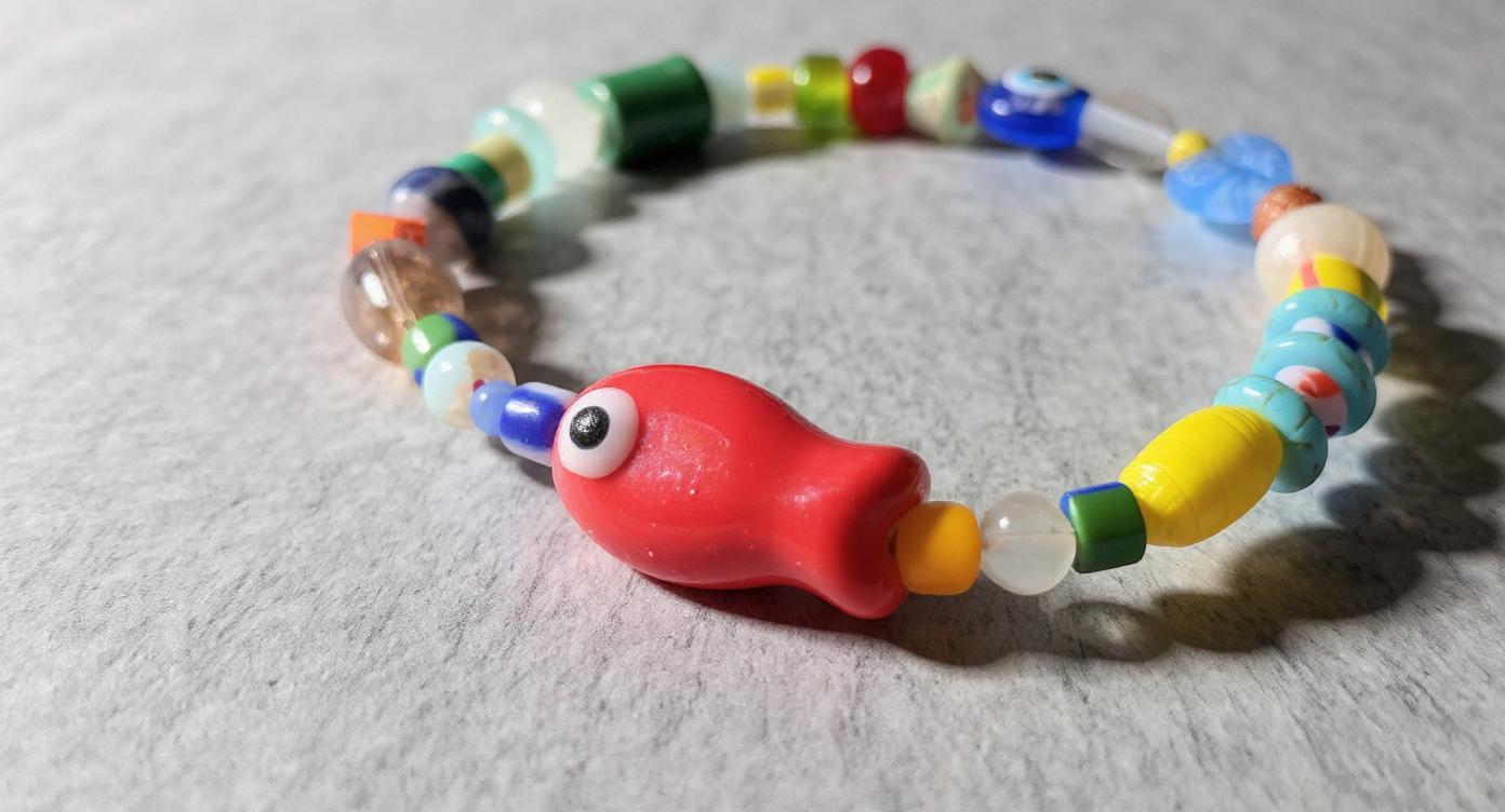 Close-up of hand painted porcelain fish bead and evil eye glass bead on stretch bracelet